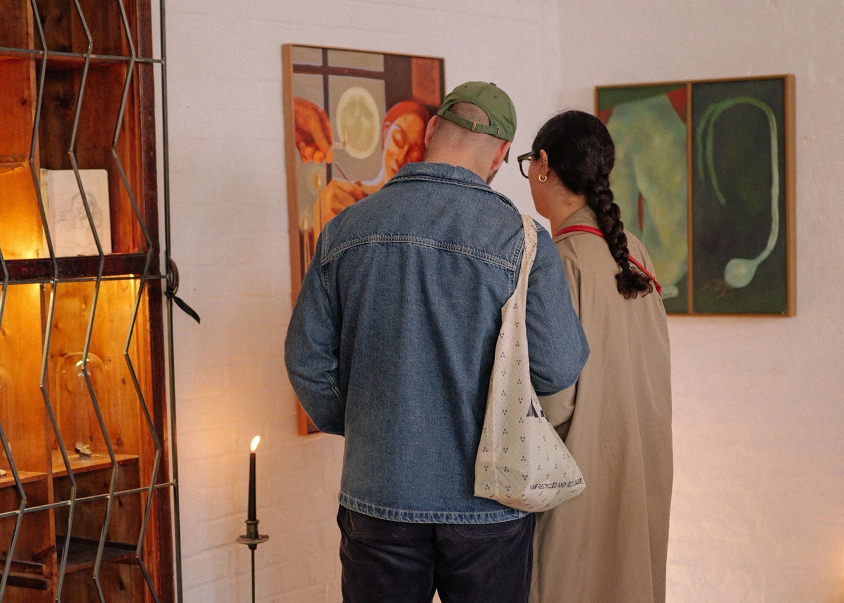 A close-up detail shot of two people engaging with the artwork at the Emblems exhibition, featured on the Partnership Editions About page.