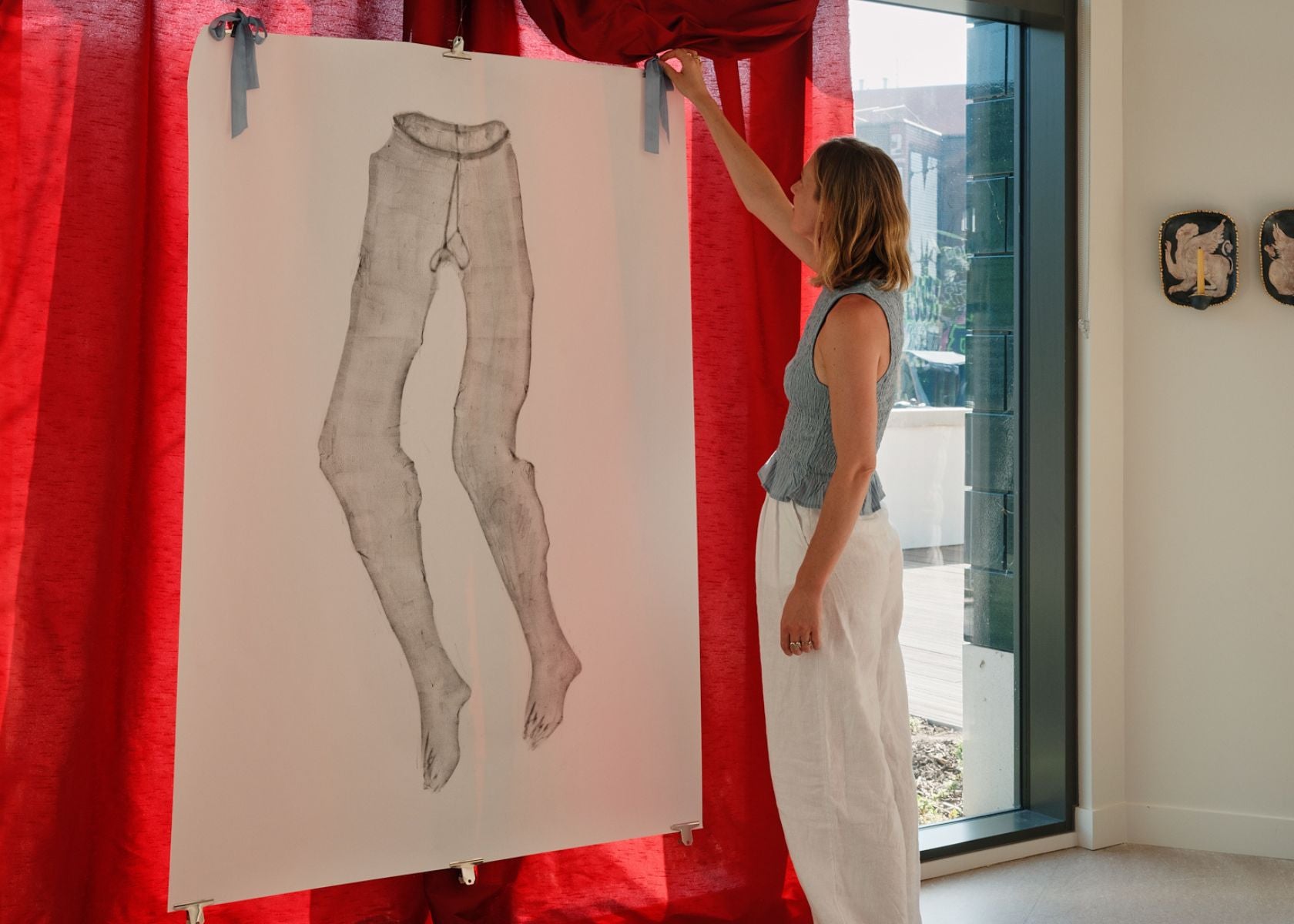 Introduction image for the Curator's Picks Dressing Up highlights, featuring founder Georgia Spray tying a bow to hang a Mae Nicolaou artwork.