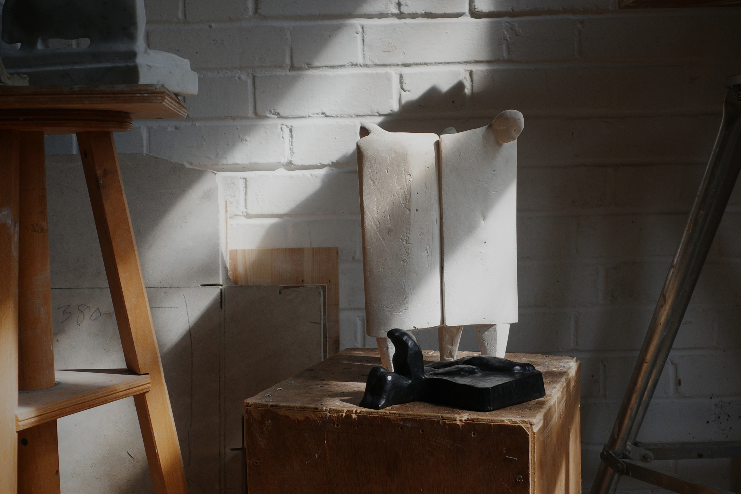 A detailed close-up shot of small figurine sculptures by Thomas Merrett in his workshop studio, featured as the header banner for the Partnership Editions Beyond The Canvas Art Edit.