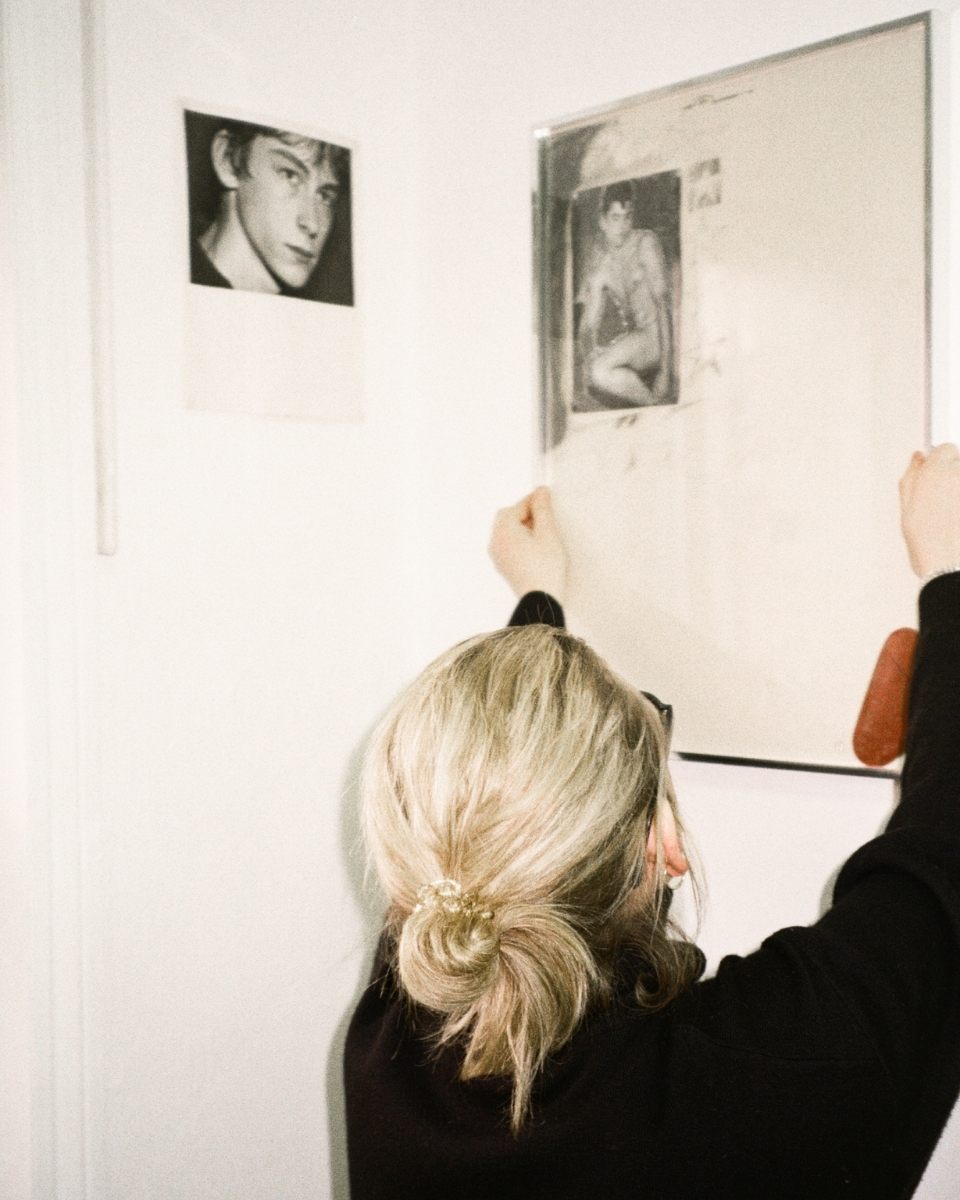 Carousel image of artist Ailsa Ogden in her studio, hanging a framed contemporary artwork on the wall for Partnership Editions.
