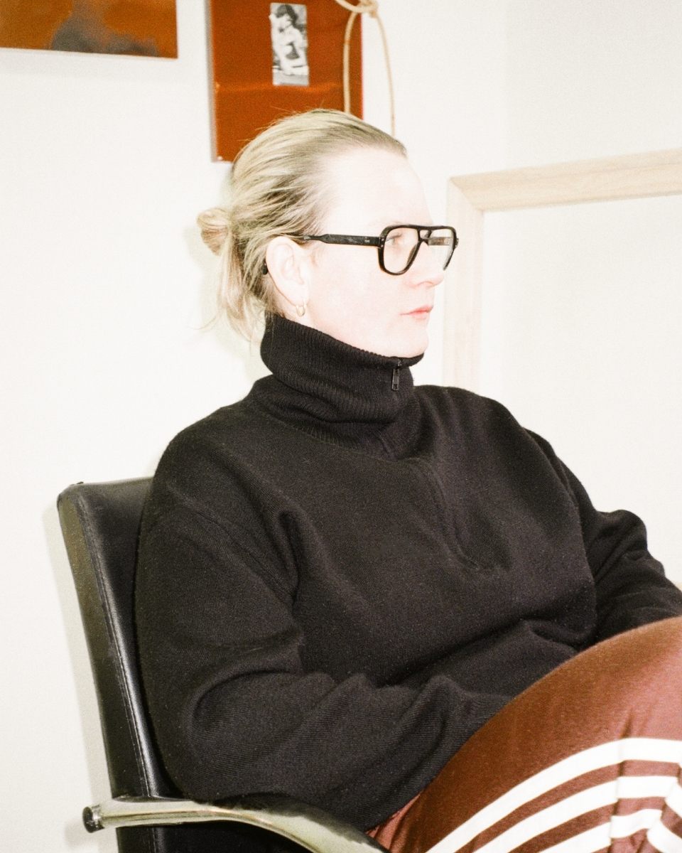 Fine artist Ailsa Ogden posing in her creative workspace in front of a studio art process wall.