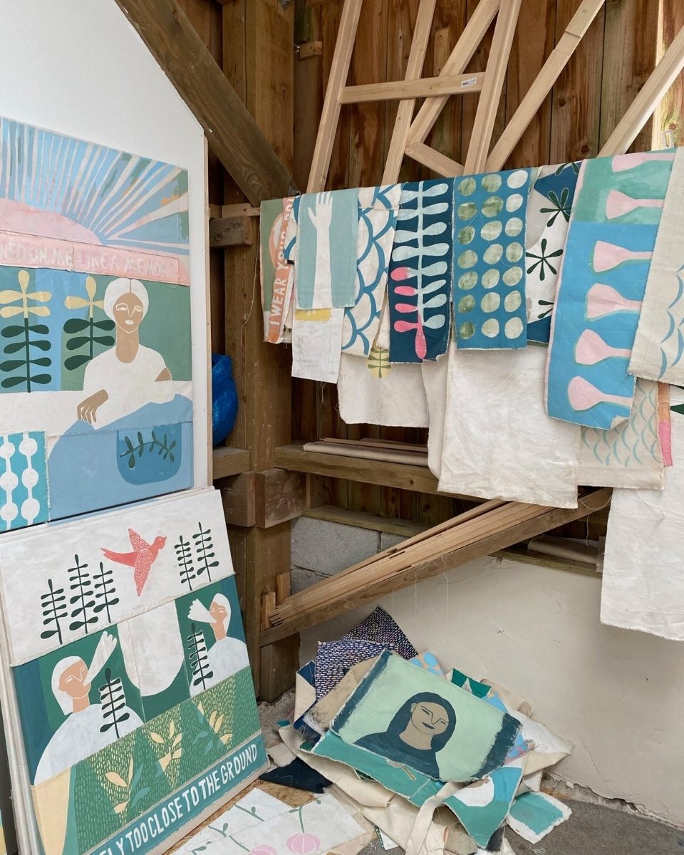 Detail of Ali Bassett’s studio showcasing finished artwork hanging on a wooden ledge and leaning pieces on the floor for Partnership Editions.