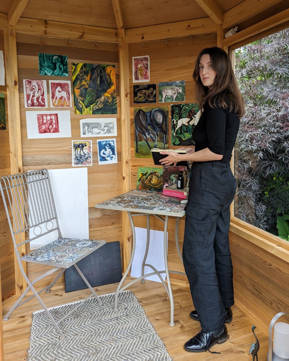 Carousel image of artist Alice Carr in her studio flicking through her sketchbook for Partnership Editions.