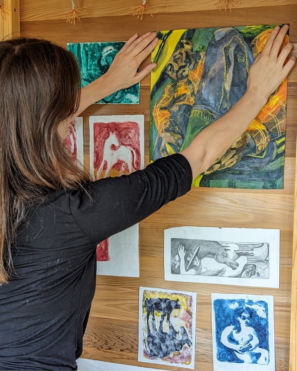 Carousel image of artist Alice Carr arranging a contemporary print on her studio wall alongside other artworks for Partnership Editions.