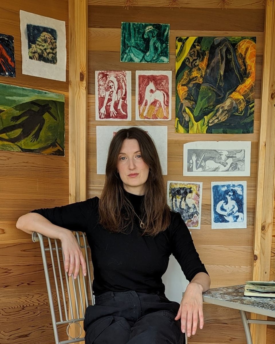 Fine artist Alice Carr posing in front of her artwork inside her creative Edinburgh painting studio.