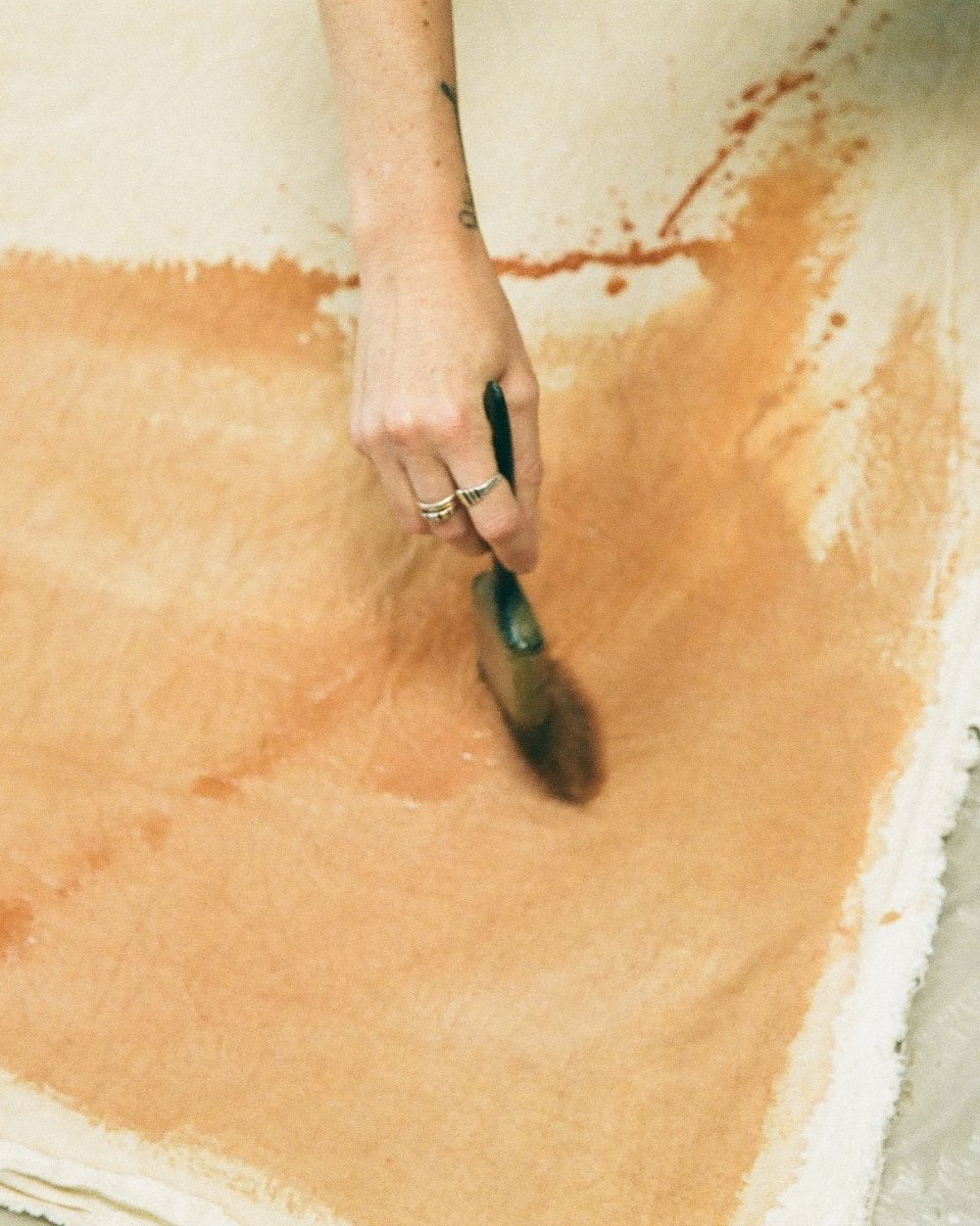 Close-up image of Alina Welch's hand applying paint to a canvas, showcasing her brushwork for Partnership Editions.