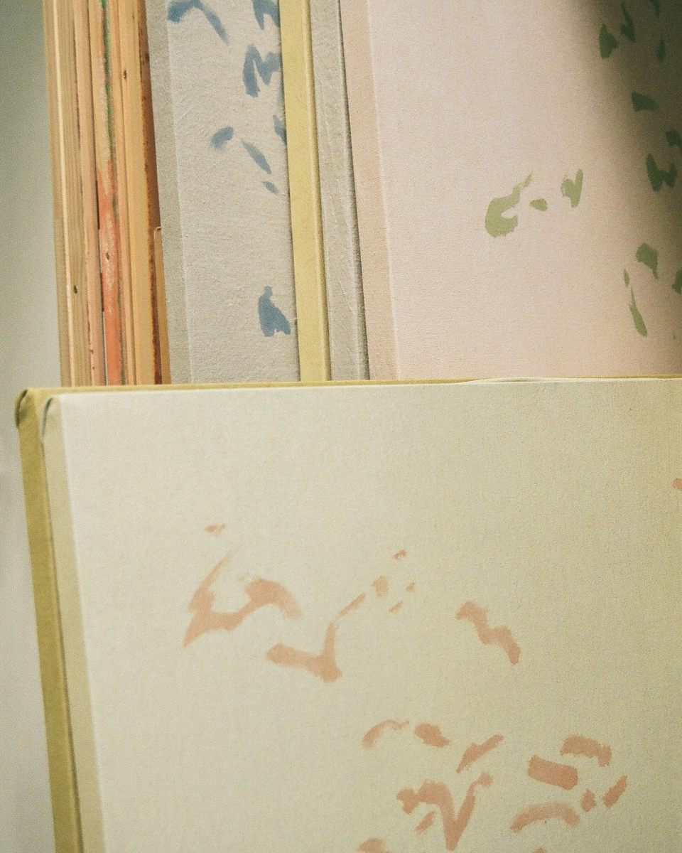 Detail shot of several completed contemporary canvases leaning against each other in Alina Welch’s studio for Partnership Editions.