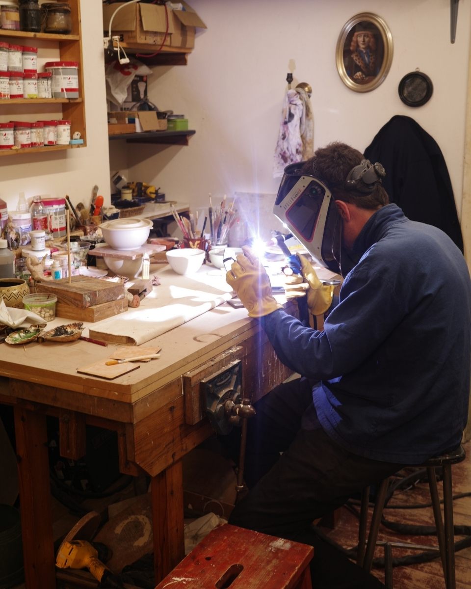 Detail shot of artist Benedict working in the studio wearing a protective spark mask for Partnership Editions.