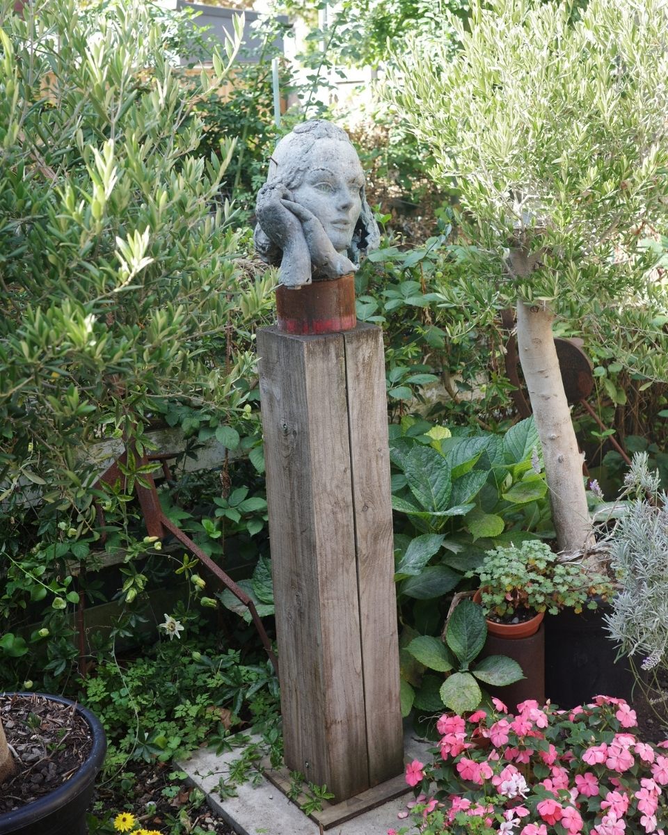 Outdoor lifestyle shot of a contemporary sculpture by Amata Benedict displayed on a weathered wooden pillar for Partnership Editions.