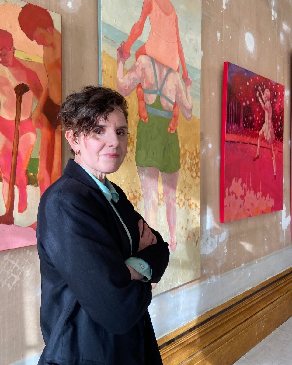 Portrait of artist Amy Dury in her studio, posing in front of her large-scale figurative artworks for Partnership Editions.