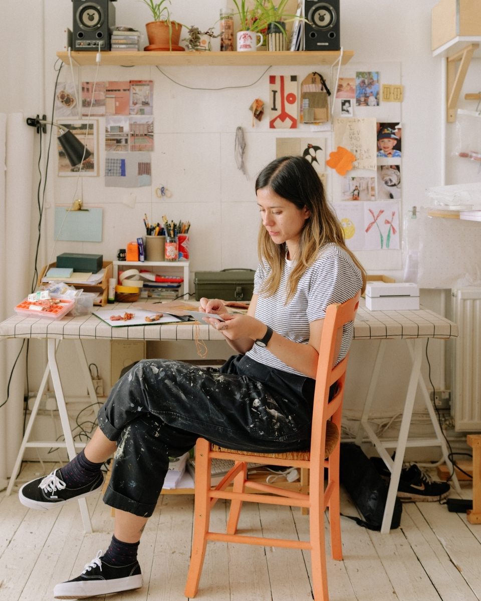 Portrait of artist Ann-Marie Williamson sitting at her studio desk working on a new piece for Partnership Editions.