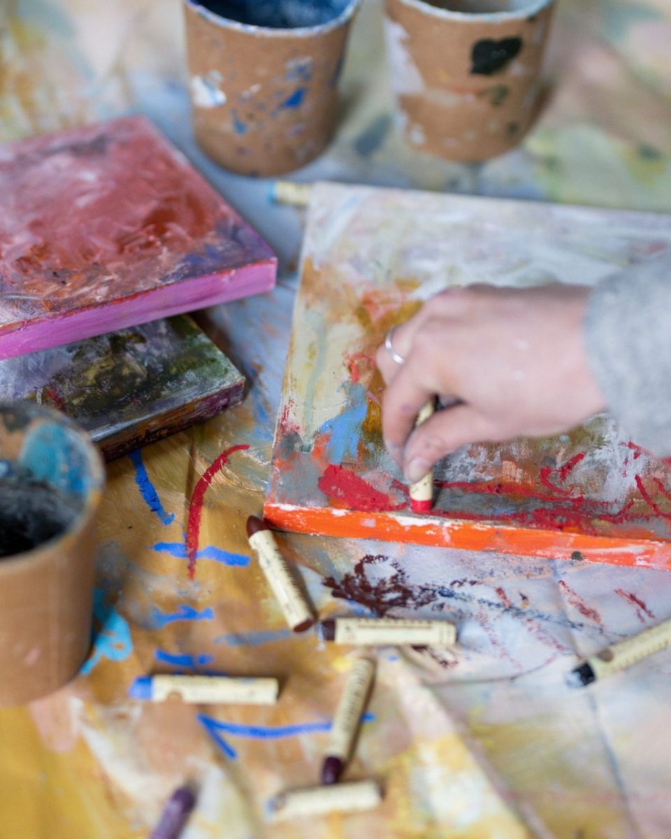 Carousel image of artist Bethany Holmes in her studio using colourful chalks used in her creative process for Partnership Editions.