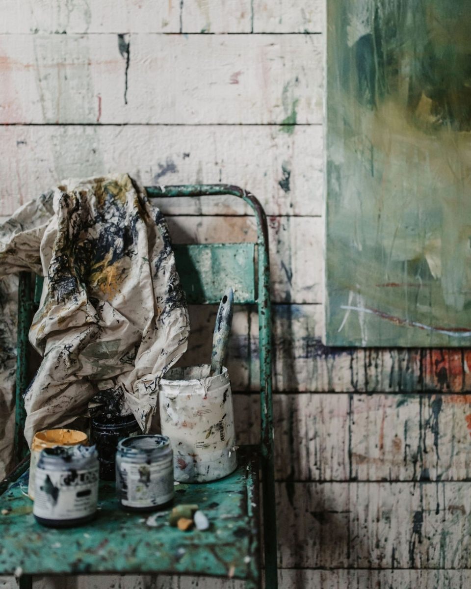 Close-up detail shot of paintbrushes, liquid paints, and a stained cloth in Bethany Holmes’ artist studio for Partnership Editions.