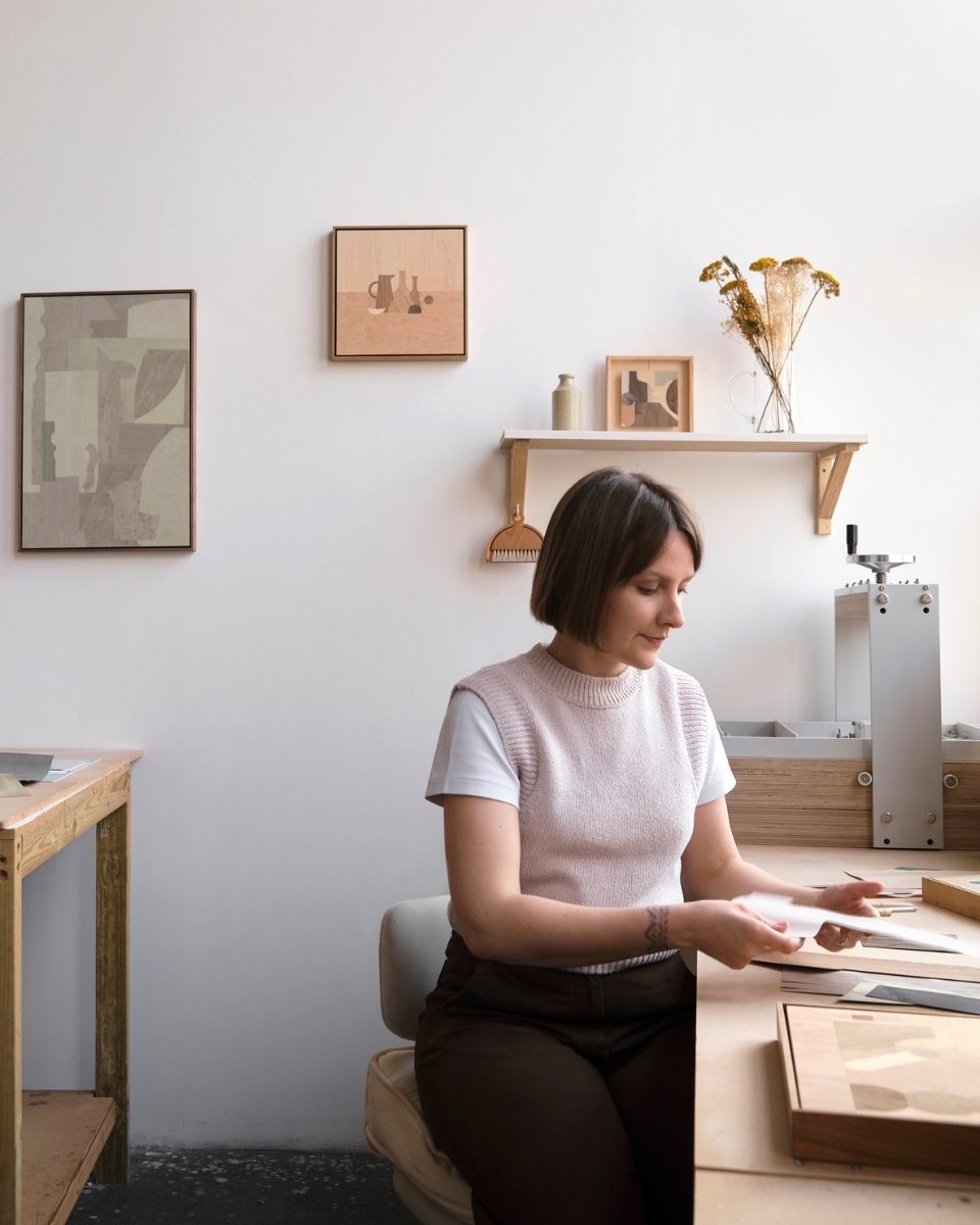 Portrait of artist Chelsea Vivash sitting at her studio desk, working on a contemporary marquetry piece for Partnership Editions.
