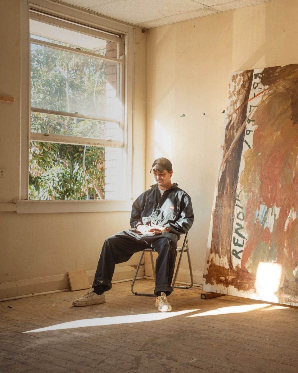 A seated portrait of artist Darcy McCrae inside his bright Northern Rivers art studio workspace.