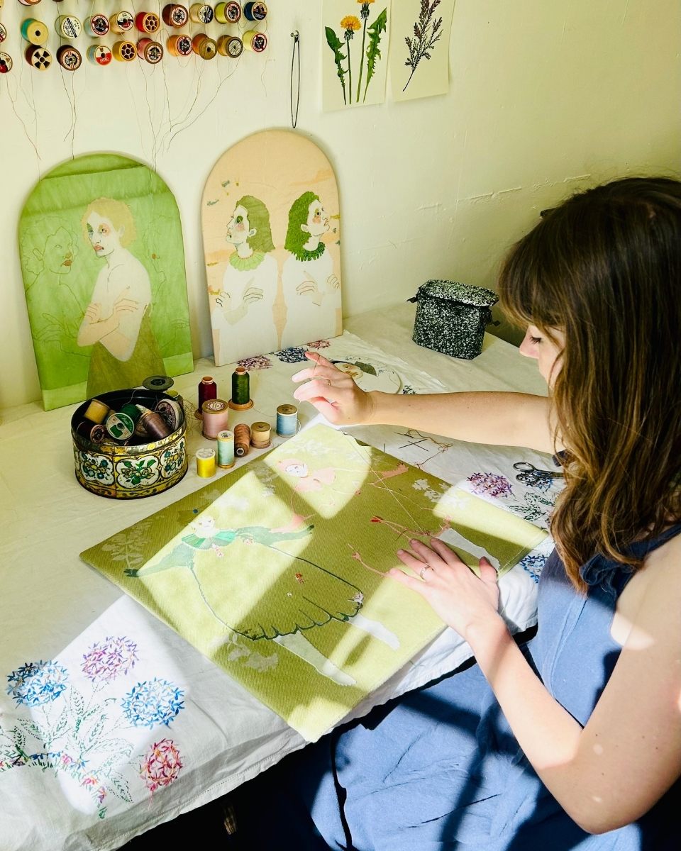 Detail shot of Elizabeth Loveday using hand-stitching and embroidery threads on a reclaimed fabric piece in her studio for Partnership Editions.
