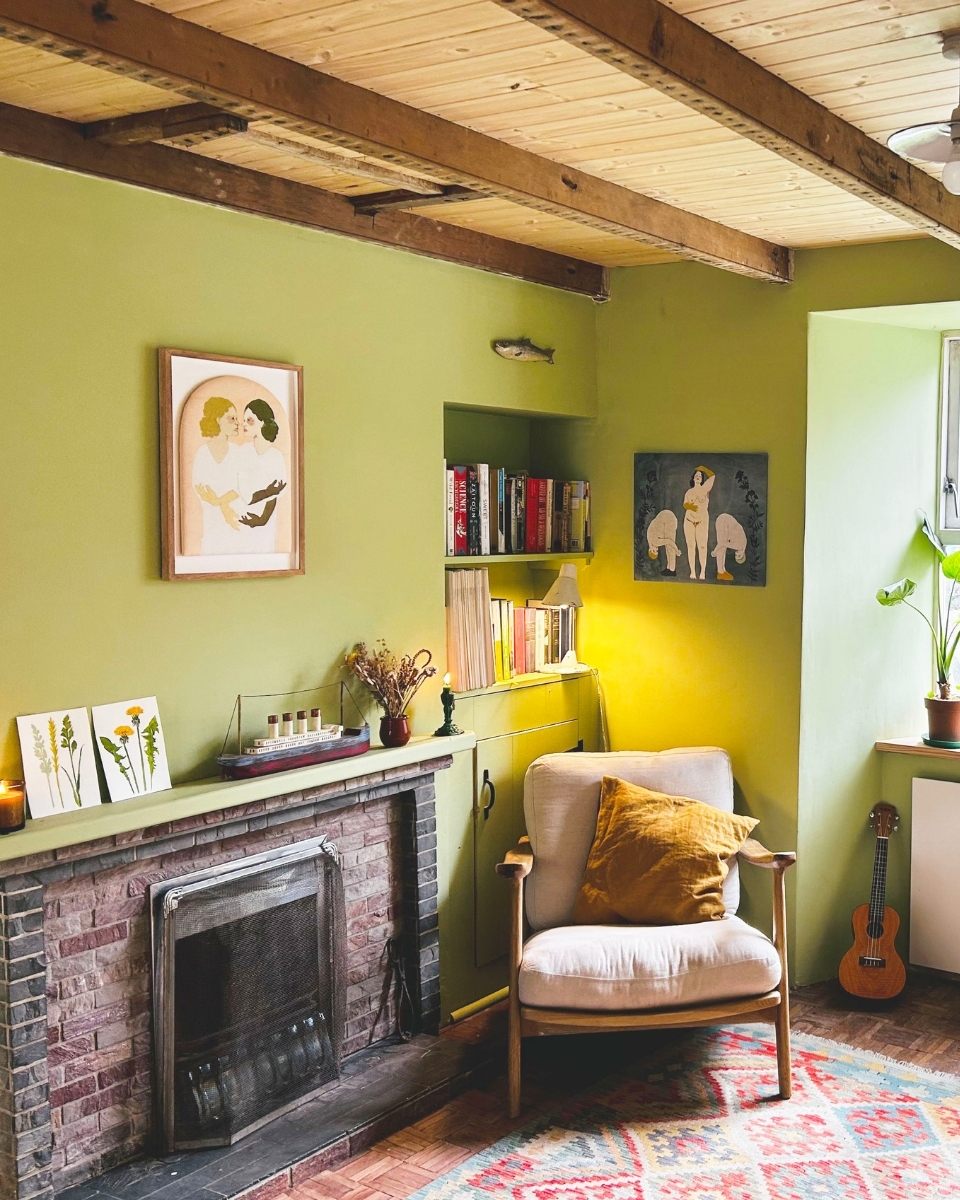 Elizabeth Loveday Living room with framed artwork, green walls, a fireplace, and a chair with a yellow pillow.