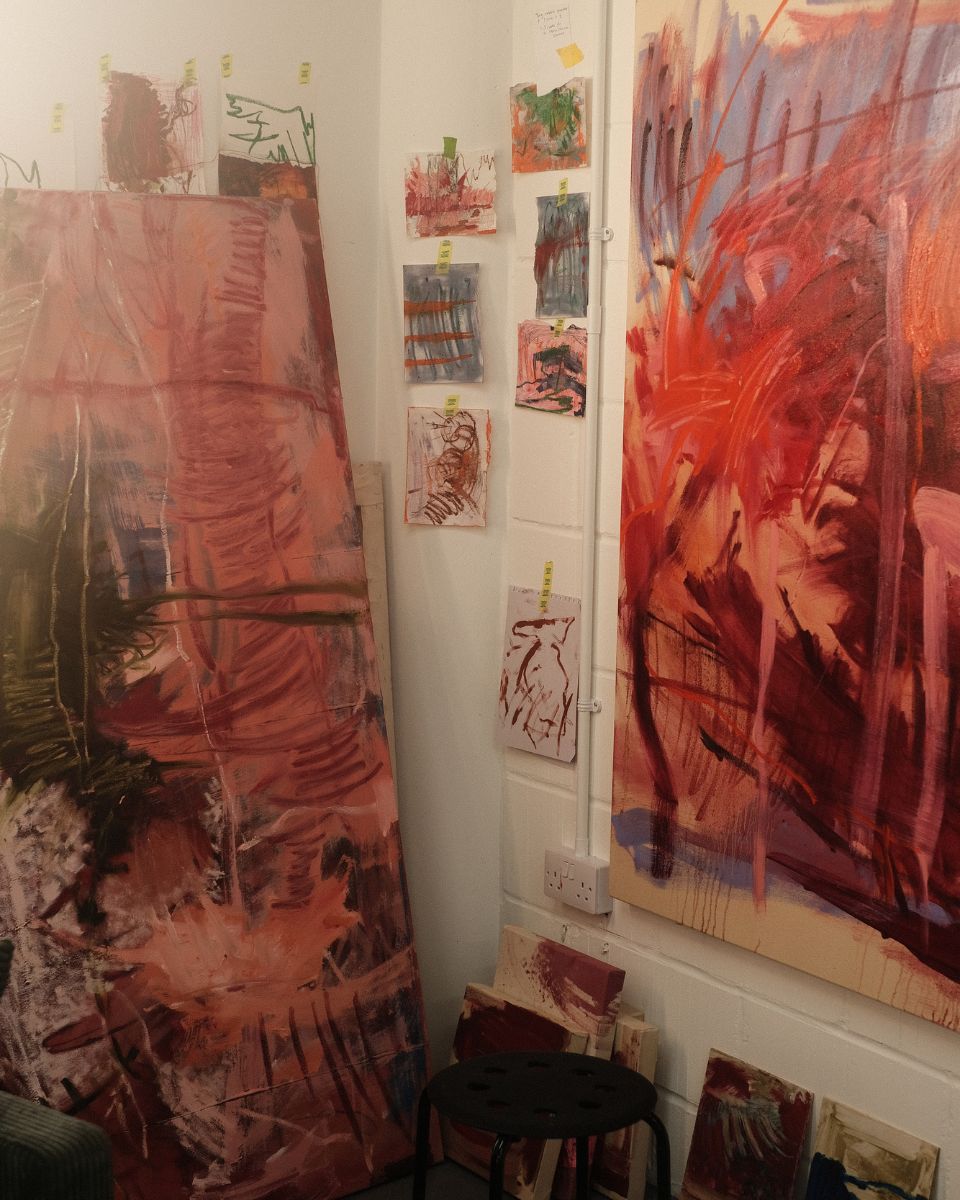 Small colour studies, paper sketches, and large abstract canvases displayed on artist Ellie Walker's studio wall.