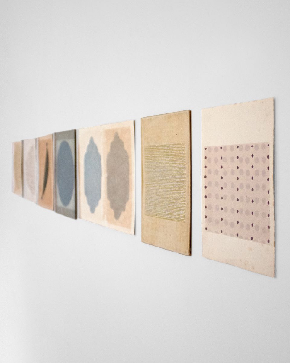 A series of unframed abstract screenprints by Emma Lawrenson arranged in a straight line on a white wall.