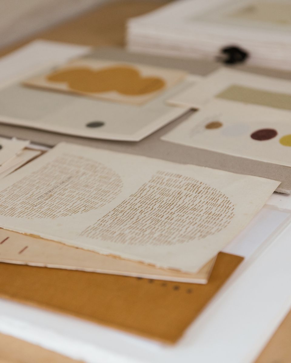A selection of abstract screenprints arranged across a wooden studio worktable by Emma Lawrenson.