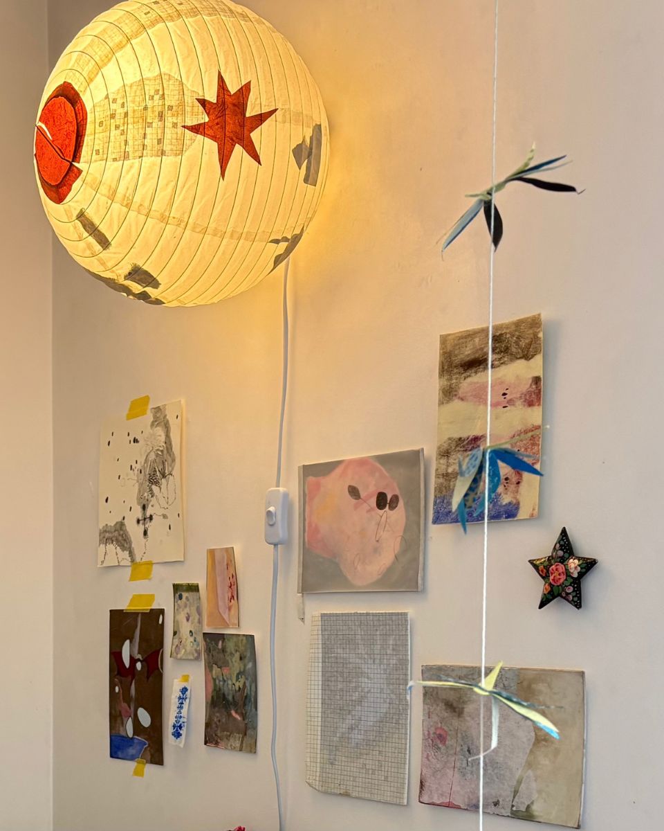 Collection of paper drawings, colour studies, and hanging paper lanterns on Esme McMillan-Scott's studio wall.