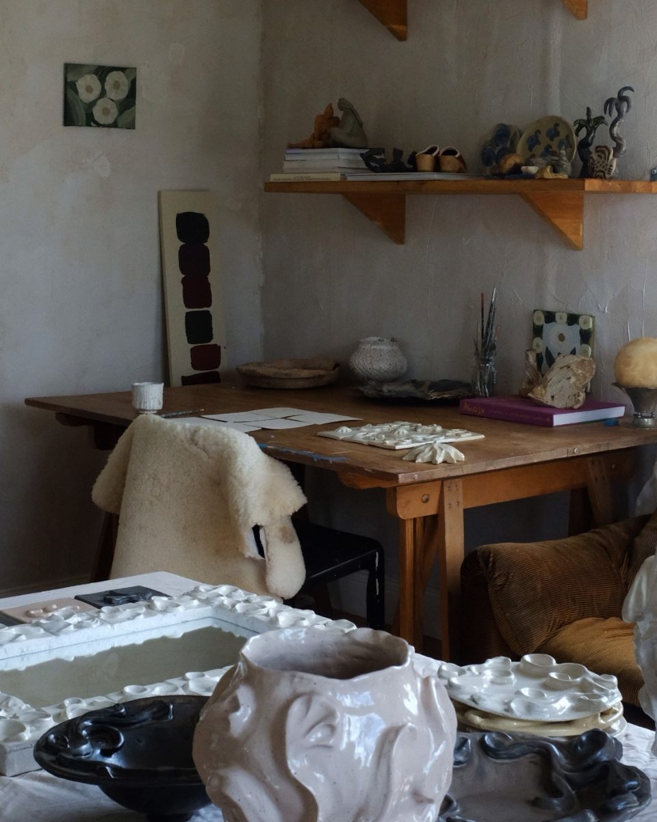 Studio shot of Fanny Schultz’s workspace, showcasing her desk and various floral relief ceramic works for Partnership Editions.