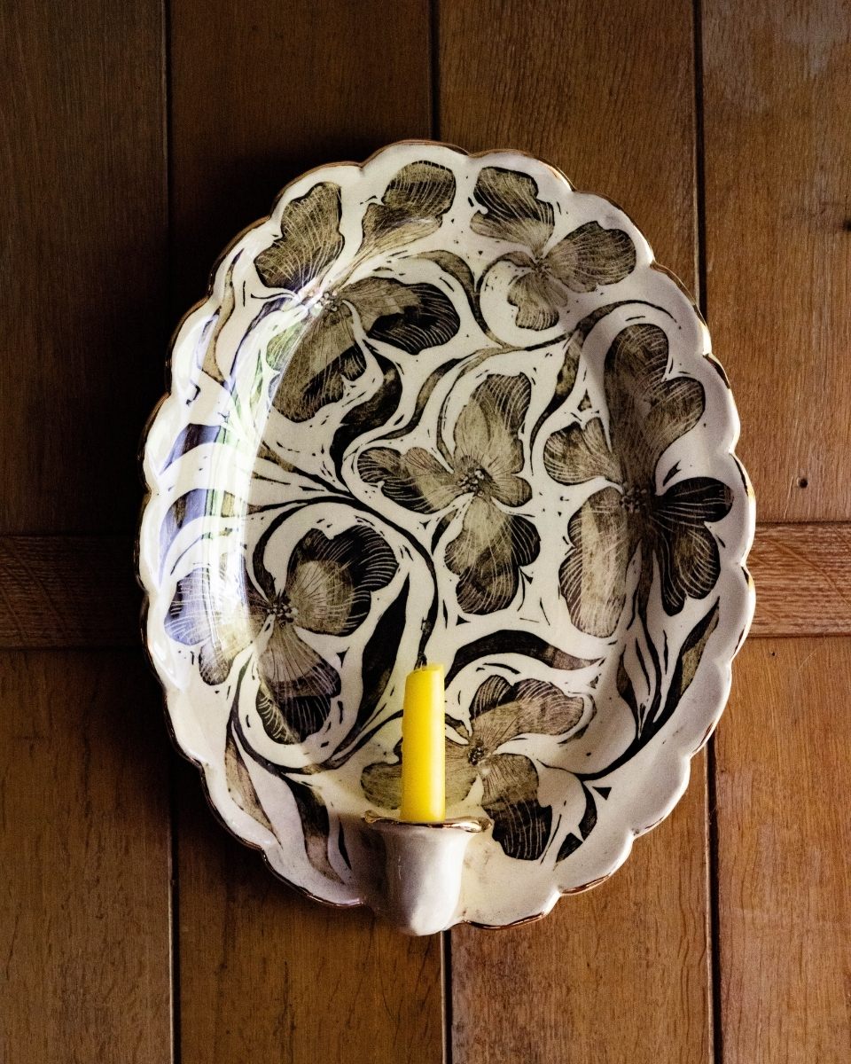 Carousel image of a hand-painted ceramic sconce plate with integrated candle holder by Freyja Lee, mounted on a home wall for Partnership Editions.