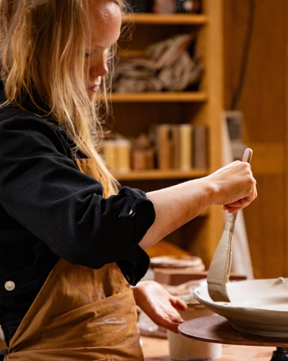 Artist Freyja Lee working in her North Wales home studio, shaping leather-hard clay plates for her latest Partnership Editions collection.