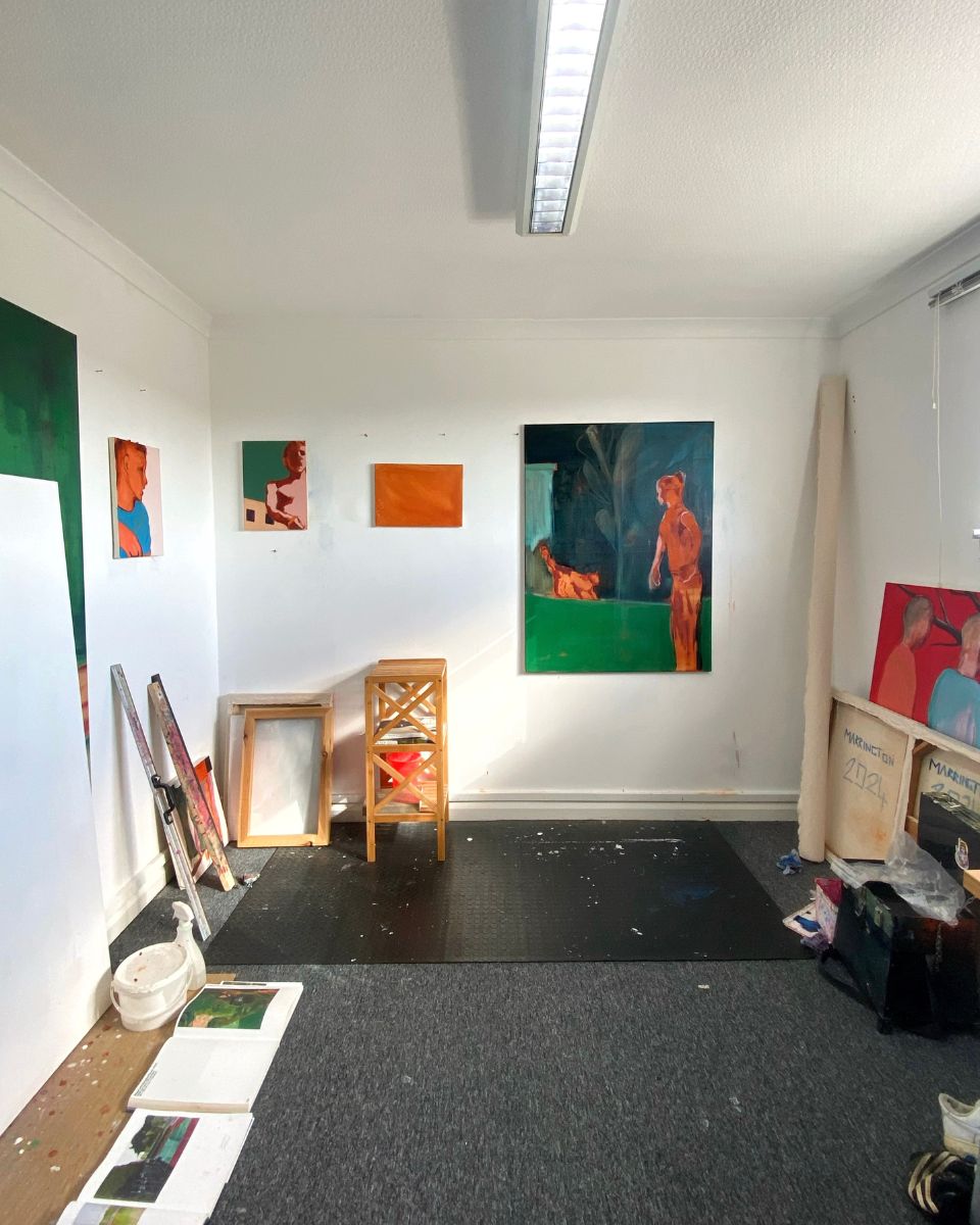 George Marrington’s art studio filled with reference books, stretched canvases, and rolled canvas.