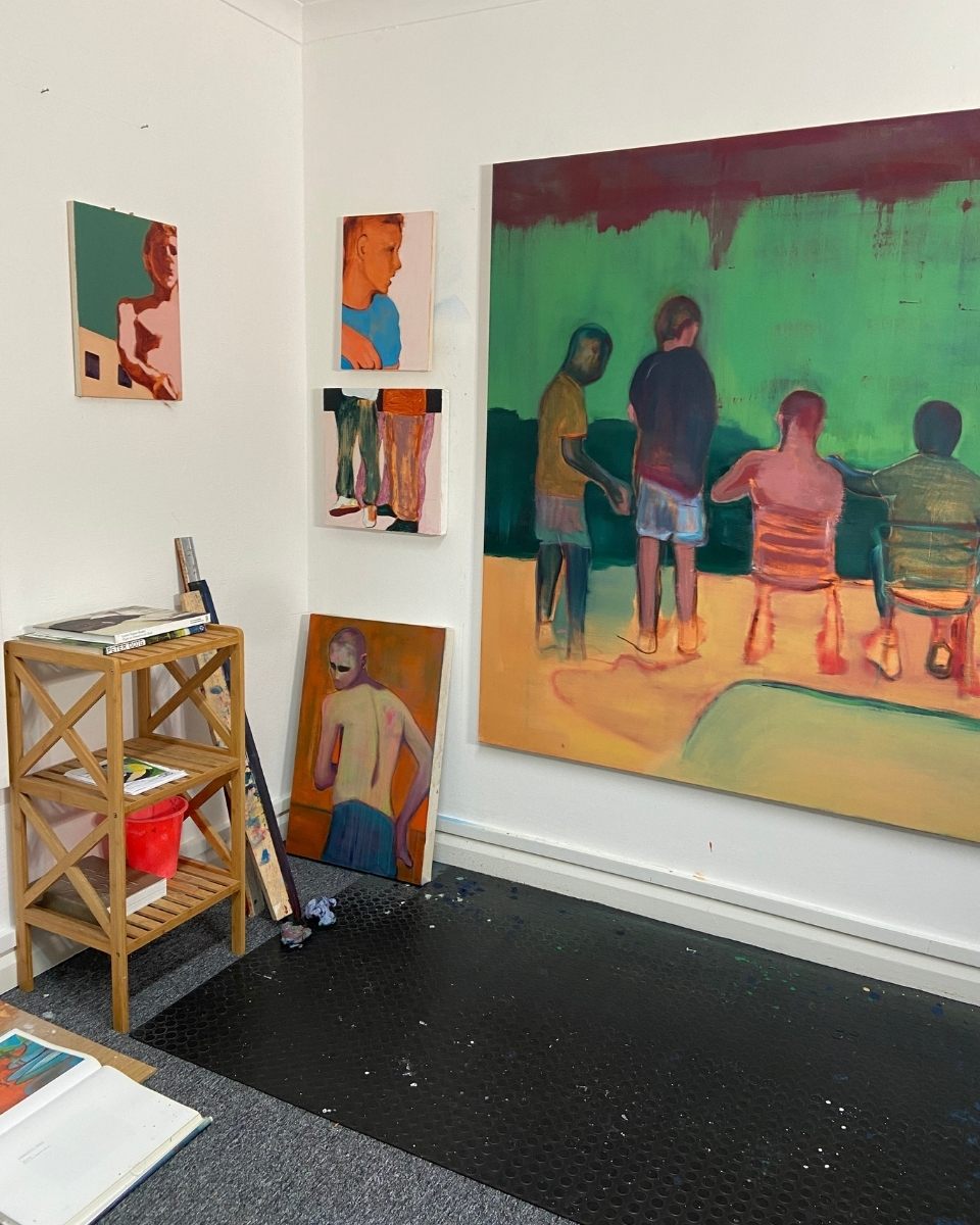 George Marrington’s large mounted canvas painting on a studio wall alongside smaller art and a wooden bookshelf.