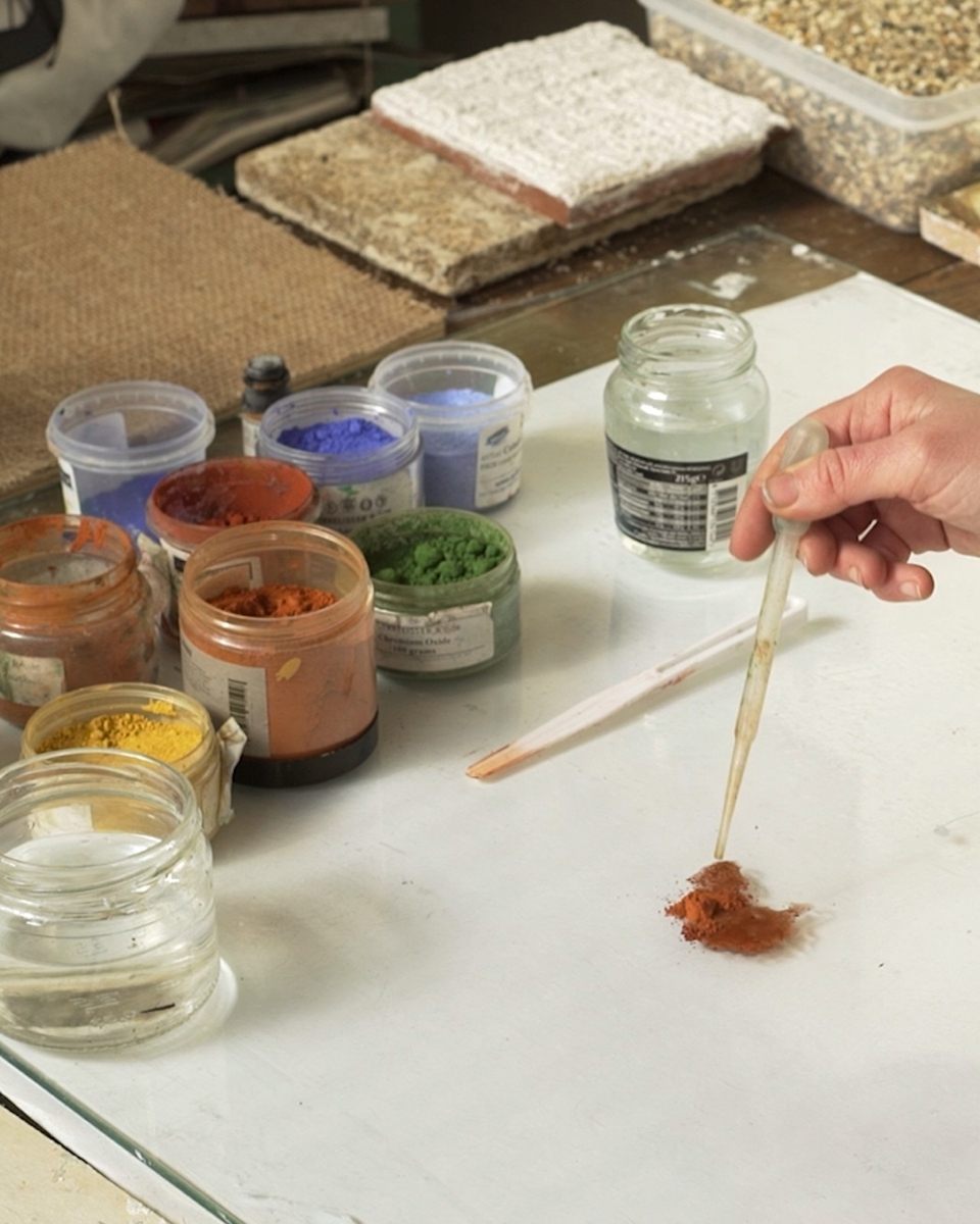 Close-up carousel image of Grace Crabtree’s hand mixing raw earth pigments for her egg tempera paintings at Partnership Editions.