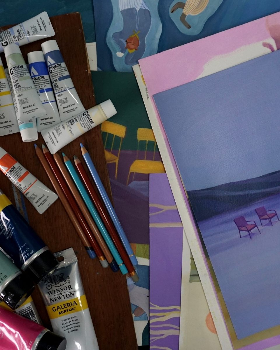 Close-up of Ifada Nisa’s studio desk featuring vibrant gouache paint tubes and finished painting snippets for Partnership Editions.