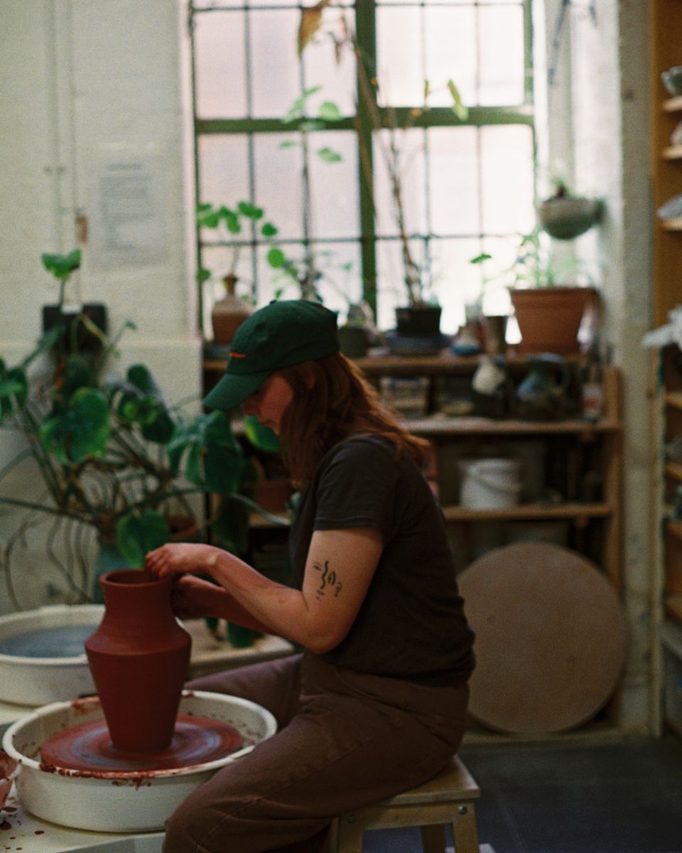 Artist Imogen Richards hand-shaping a contemporary red clay vase in her ceramic studio for Partnership Editions.