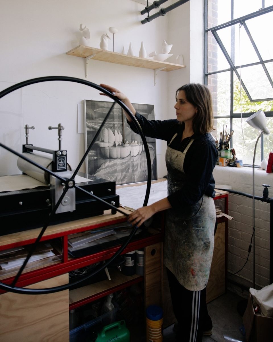 Artist Ines Fernandez de Cordova operating the spinning wheel of a traditional etching press in her London printmaking studio.