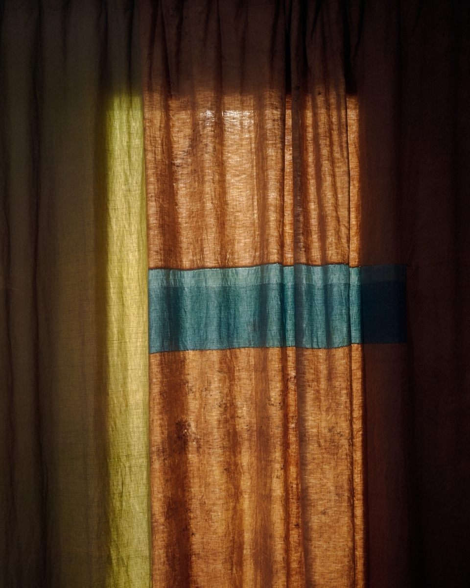 Close-up detail of a plant-dyed patchwork curtain by Isabel Farchy, showcasing the play of natural light through linen for Partnership Editions.