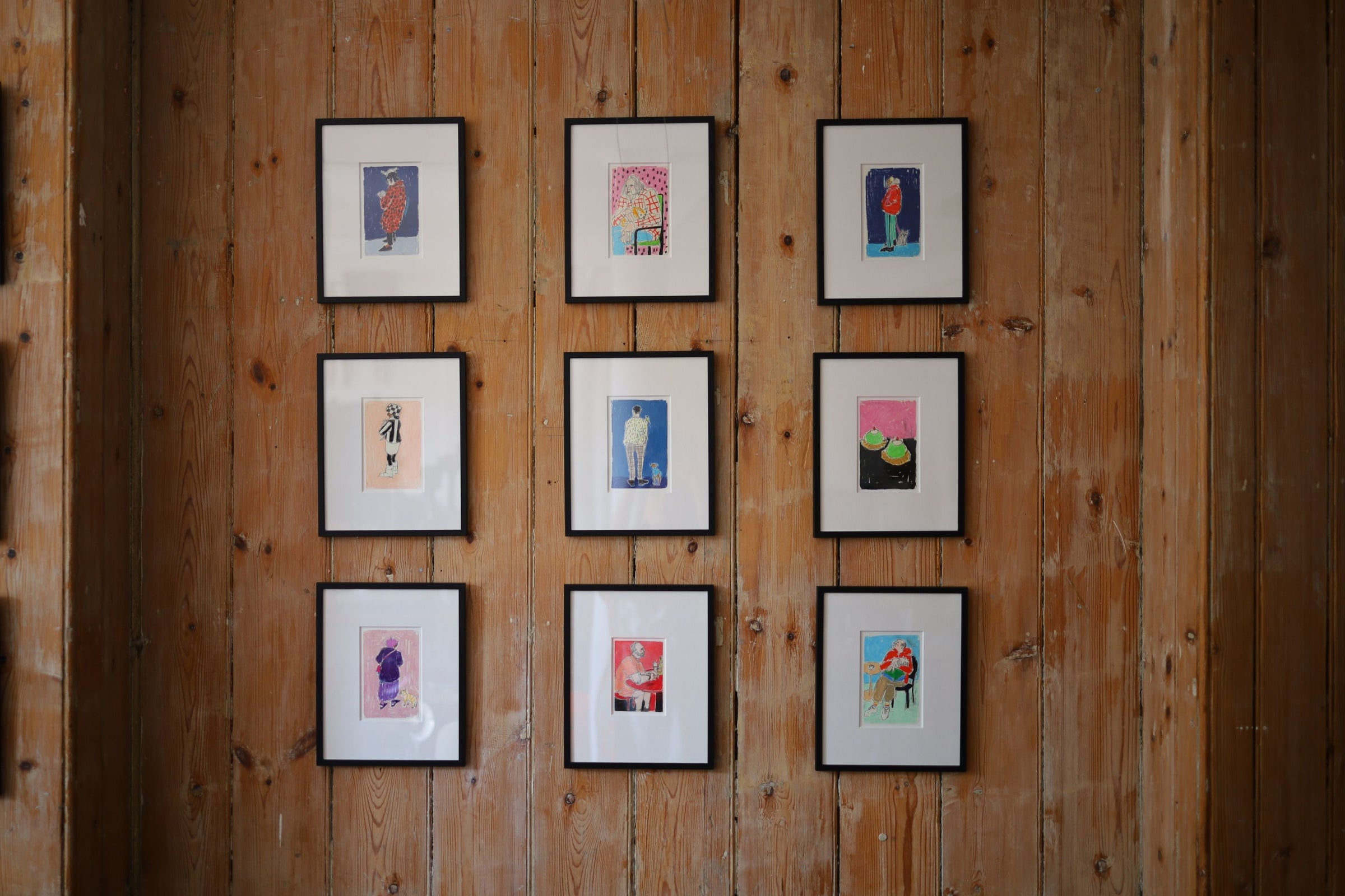 A landscape view of nine framed, colourful, small-scale original illustrations by Isabella Cotier on display at her Cafe Culture exhibition.