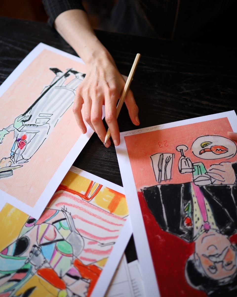Close-up detail of Isabella Cotier’s hand signing limited edition prints at New River Cafe for her Partnership Editions solo exhibition.