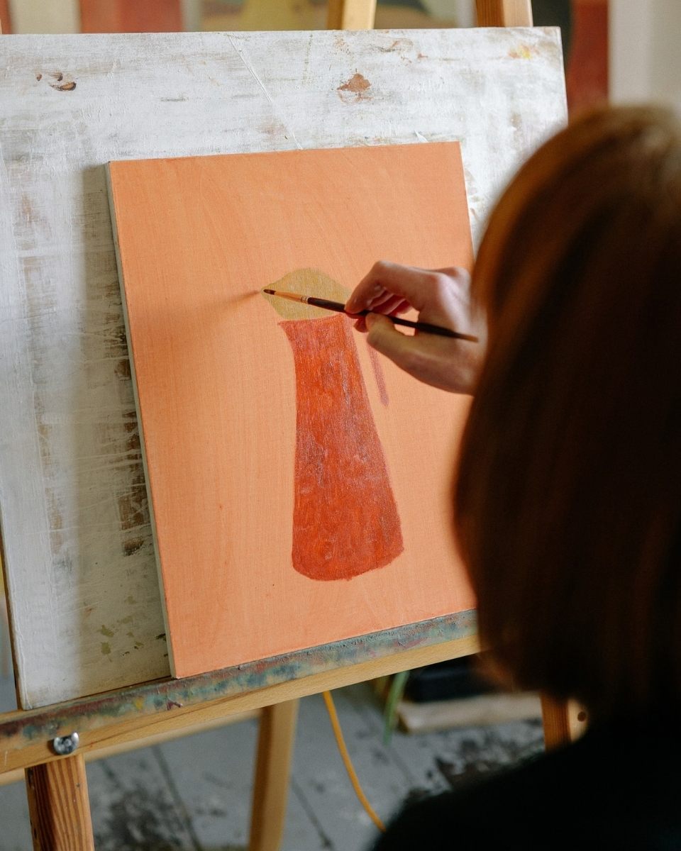 Action shot of Jay Harper applying delicate finishing touches to a contemporary still life oil painting in her studio for Partnership Editions.