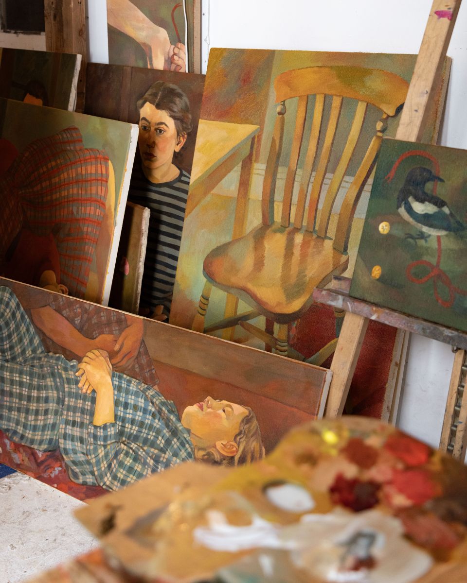 Artist Lily Snowden-Fine artwork in her studio showcasing narrative paintings leaning on the wall for Partnership Editions.