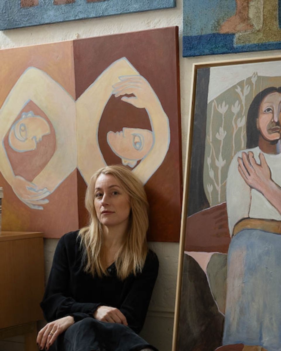 Bust portrait of artist Josefin Tolstoy posing beside her large textured paintings resting on the floor.