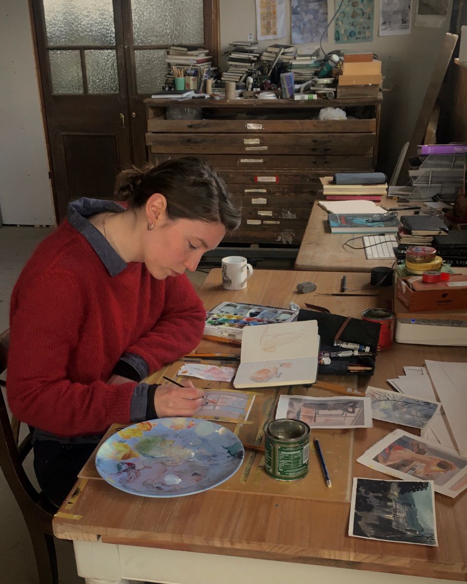 Illustrator Josephine Birch at work at her desk painting a new delicate watercolour piece in her studio.