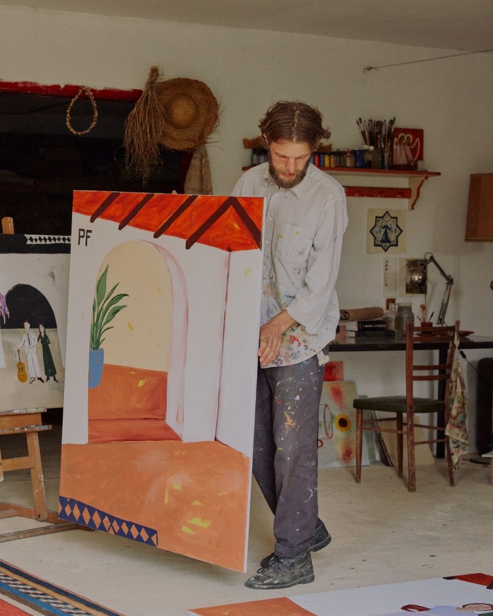 Joshua Perkin carrying a large-scale abstract landscape painting through his sun-drenched studio for Partnership Editions.