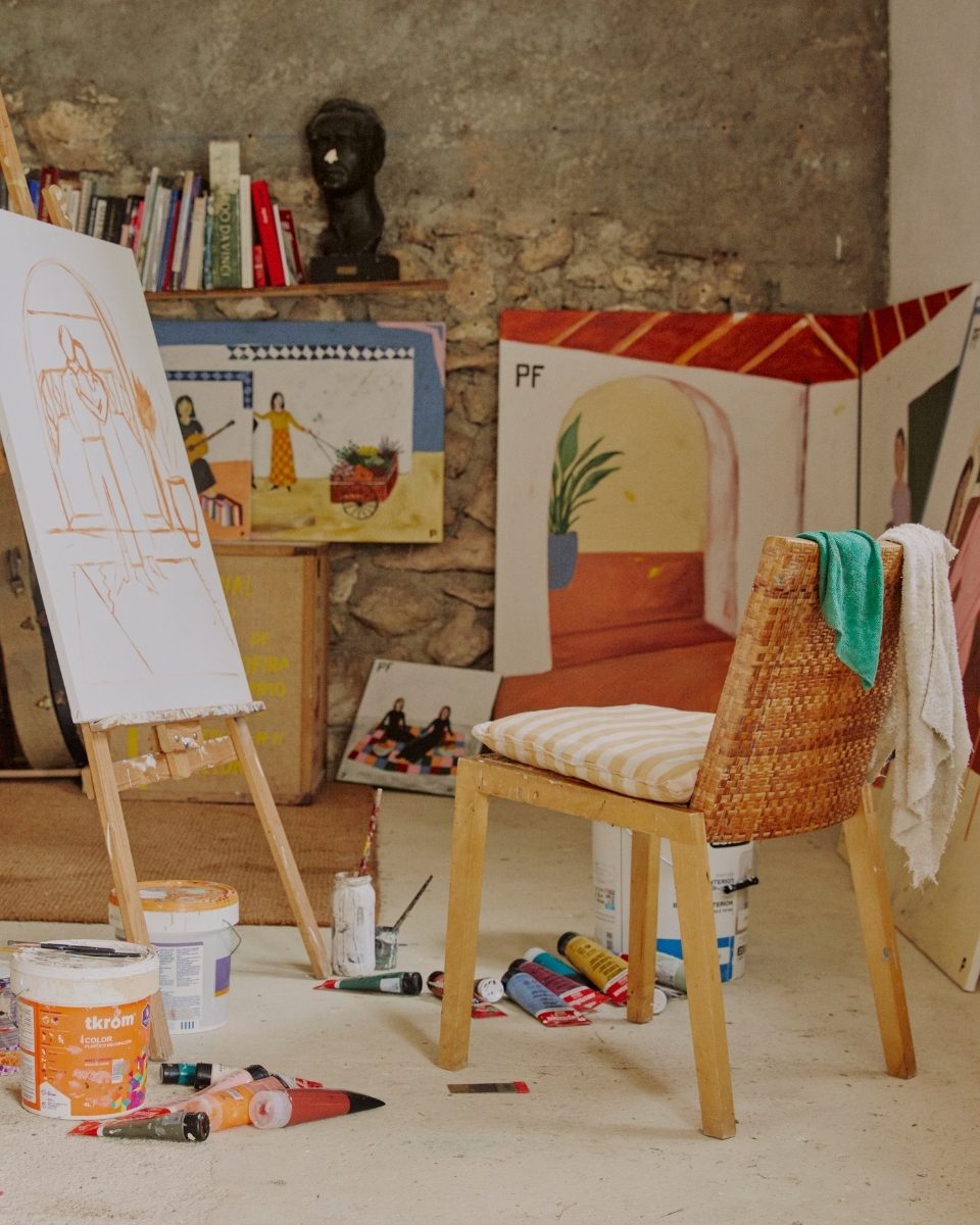 Studio snippet showing a work-in-progress painting on an easel alongside paint-stained cloths and materials for Partnership Editions.