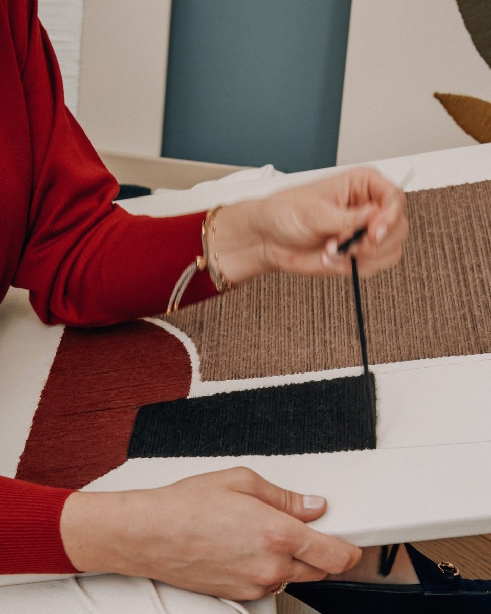 Close-up detail of Kanica’s hand embroidering an abstract canvas using natural alpaca and merino wool in her Seville studio.