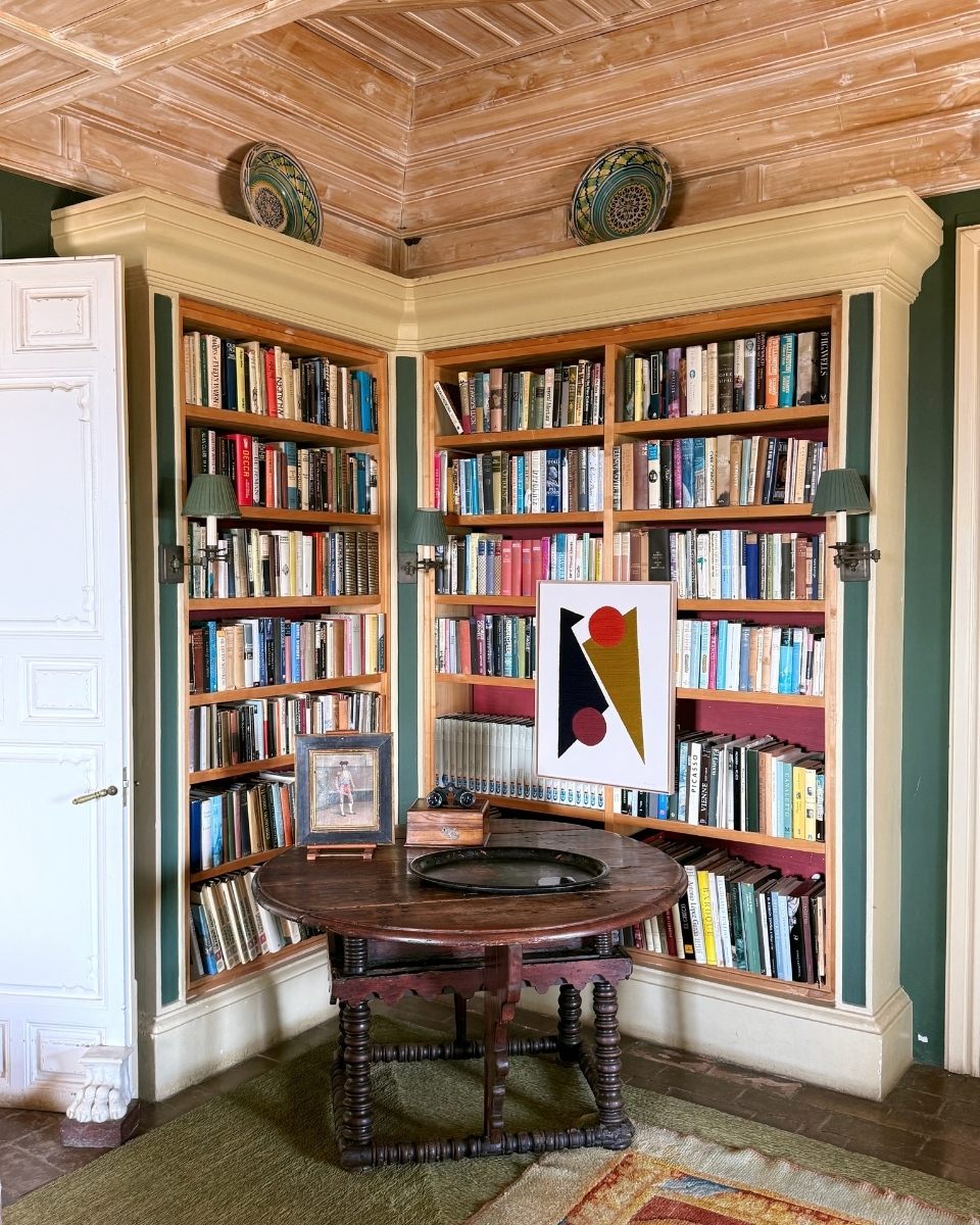 Styled wide-shot of a framed Kanica geometric textile artwork in situ within a sophisticated library space for Partnership Editions.