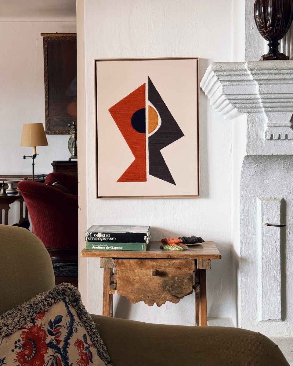 Styled shot of a framed Kanica 'Textile Geometries' artwork mounted above a wooden side table, highlighting the mid-century design aesthetic.