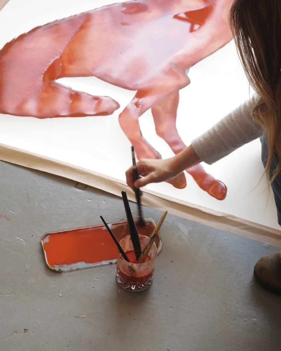Kara Marshall mixing earthy watercolour pigments on her studio floor, focusing on texture and fluid movement for her latest painting.