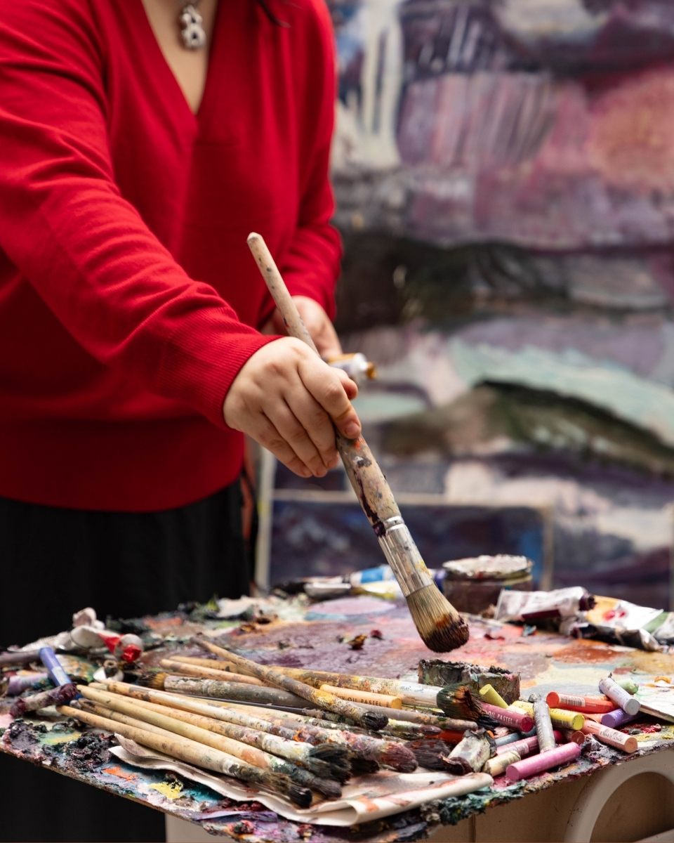 Close-up of artist Katarina Lalic's hands preparing oil paint on her palette, a foundational step in her meticulous layering process.