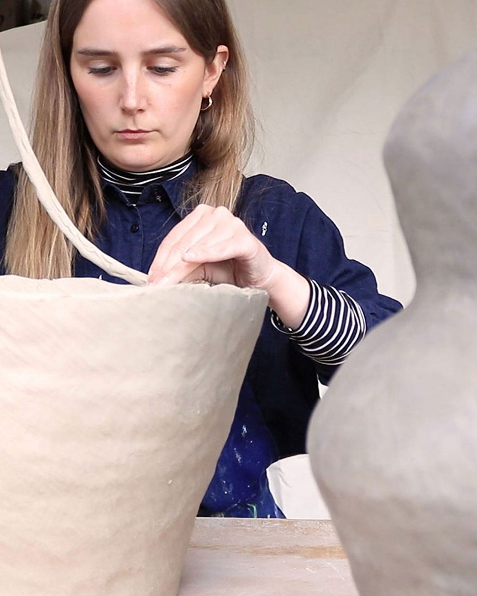 Studio portrait of Katie Moore focused on the intricate carving and shaping of a new ceramic piece for her latest collection.