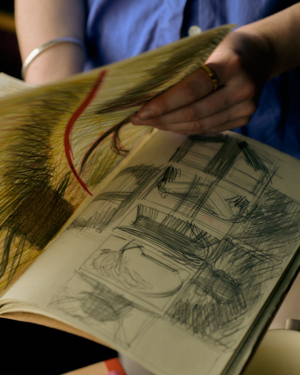 Detail of Keziah Mornin’s hand flicking through her fine art sketchbook for a Partnership Editions collection.